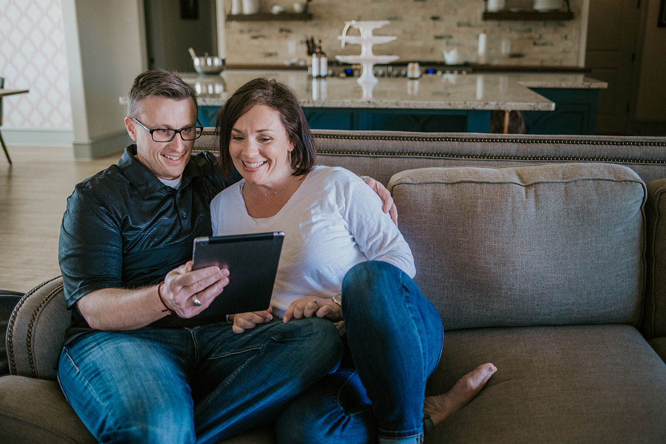 Couple sitting on the couch reading a tablet.